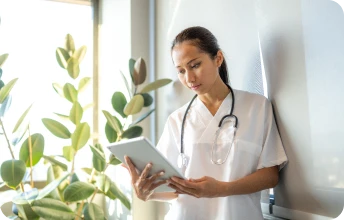 Profissional de saúde em ambiente clínico utilizando tablet, simbolizando soluções corporativas em plano de saúde Porto Seguro Empresarial